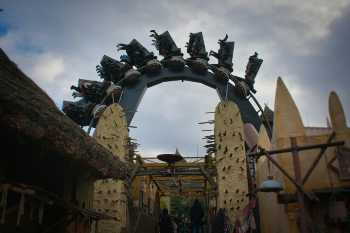 A dark roller coaster ride entrance with tribal decorations