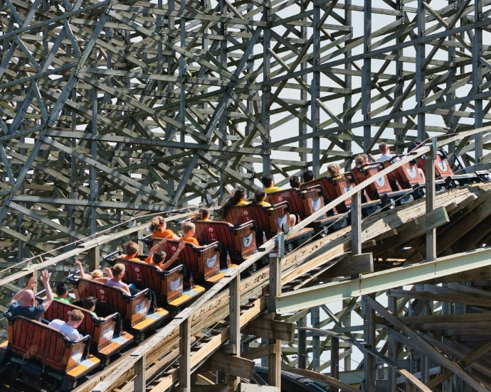 People ride a rollercoaster up a steep incline